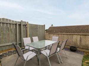 a table and chairs on a patio with a fence at Yr Hen Efail in Cemaes Bay