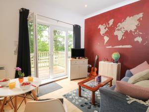 una sala de estar con una pared roja con un mapa. en Awdry Bungalow, en Beaworthy