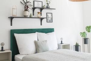 um quarto com uma cama verde e branca com almofadas brancas em Tropical Apartment em Koblenz