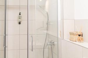 a shower in a bathroom with white tiled walls at Tropical Apartment - für Freunde & Familien, stadtnah, Parkplatz, E-Ladestation, Gitterbox für Fahrräder, Fitnessstudio, digitale Gästemappe mit Restaurant- und Unternehmenstipps in Koblenz +29 photos