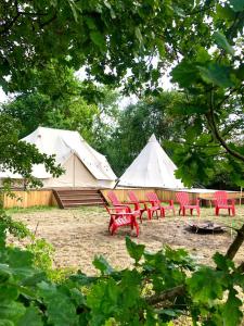 un gruppo di sedie rosse e tende bianche di Cowcooning / Family tents a Huldenberg