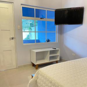 a bedroom with a bed and a tv and a window at Hotel Mono Azul in Quepos