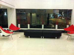 a living room with a black couch and red chairs at French Hotel in Ipoh
