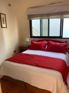 a bedroom with a large bed with red pillows and a window at Hotel Marina Azul in Viña del Mar