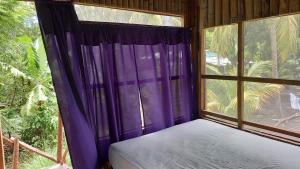 Schlafzimmer mit einem großen Fenster mit lila Vorhängen in der Unterkunft Cabañas Privadas Dilany in Moyogalpa