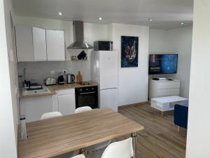 a kitchen with a table and chairs and a refrigerator at La Maison 19 : Studio 2 personnes Louvre Lens in Lens