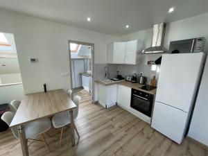 a kitchen with a table and a white refrigerator at La Maison 19 : Studio 2 personnes Louvre Lens in Lens +4 photos