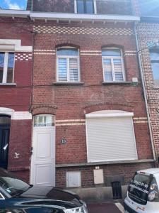 a brick building with a white door and windows at La Maison 19 : Studio 2 personnes Louvre Lens in Lens