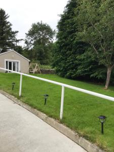 a white fence in the grass next to a house at Carney Apartment in Ardara