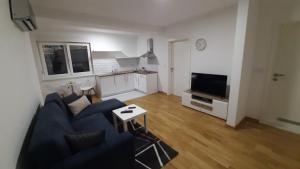 a living room with a blue couch and a kitchen at Apartman 222 in Brčko