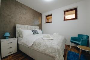 a bedroom with a bed and a blue chair at MB Hedonic Apartman in Vrnjačka Banja