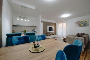 a dining room and living room with a table and blue chairs at MB Hedonic Apartman in Vrnjačka Banja