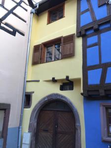 żółty budynek z drewnianymi drzwiami i oknami w obiekcie Gîte Elisa et léna w mieście Riquewihr