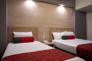 a hotel room with two beds with red and white sheets at Hotel Roble in Mexico City