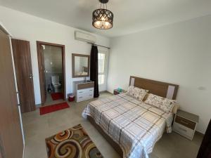 Amwaj Seaside Retreat- Luxury 2BR Chalet in Amwaj Sidi Abdelrahman في العلمين: غرفة نوم بسرير ومغسلة ومرآة