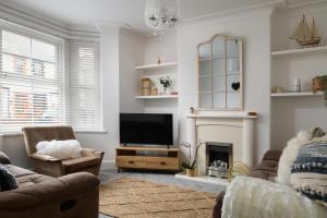 uma sala de estar com televisão e lareira em Modern, light and airy townhouse in Llandudno, West Shore em Llandudno