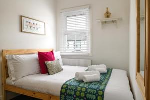 um pequeno quarto com uma cama com almofadas em Modern, light and airy townhouse in Llandudno, West Shore em Llandudno