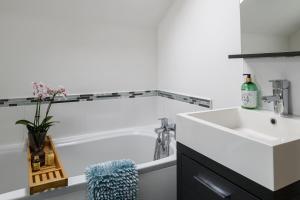 uma casa de banho com uma banheira branca e um lavatório. em Modern, light and airy townhouse in Llandudno, West Shore em Llandudno