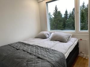 a bed in a room with a large window at Moderni ullakkohuoneisto in Kuopio