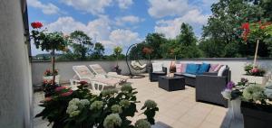a patio with couches and chairs and flowers at Apartman Japanski vrt, Centar in Vrnjačka Banja