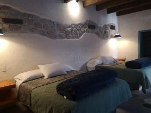 a bedroom with two beds and a stone wall at Hotel Pepen in San Cristóbal de Las Casas