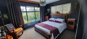 a bedroom with a bed and a chair and a window at Waitapu Springs B&B in Takaka