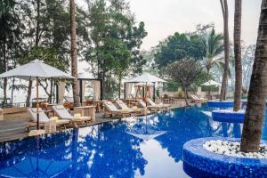 a pool at a resort with chairs and umbrellas at Silver Waves Resort & Spa Daman, a member of Radisson Individuals in Daman