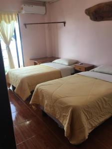 um quarto de hotel com duas camas e uma janela em Hostal Nathaly em Puerto Baquerizo Moreno