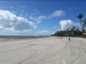 a person walking on a sandy beach with palm trees at Axé Mainha Flats! Quarta Praia! in Morro de São Paulo