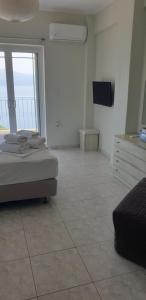a bedroom with a bed and a television and a tiled floor at Beachfront Houses in Pogoniá