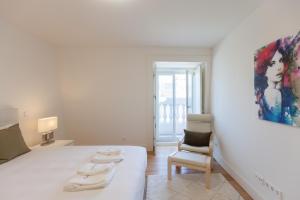 een witte kamer met een bed en een schilderij aan de muur bij FLH Praça Comércio Artistic Flat with Balcony in Lissabon
