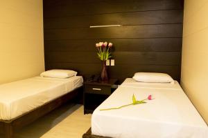 two beds in a room with a vase of flowers on a table at Sulit Place in Manila
