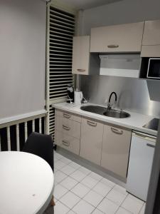a kitchen with white cabinets and a sink and a table at Résidence Marinotel in Le Diamant