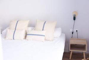 a white bed with white pillows and a night stand at Apartamento ático en el casco antiguo in Mataró