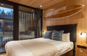 Schlafzimmer mit einem Bett mit einem Surfbrett an der Wand in der Unterkunft Mackenzie Beach Resort in Tofino