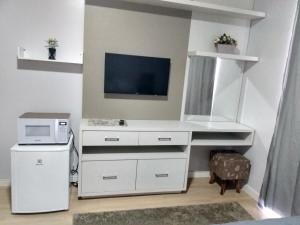 Habitación con escritorio blanco con microondas y TV. en Cantinho da Vila Hospedagem, en Penha