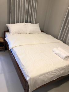 a bed with white sheets and pillows on it at Treuy Koh Bungalow in Kampot