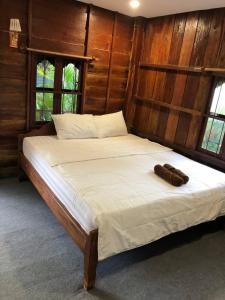 a bedroom with a bed with white sheets and two windows at Treuy Koh Bungalow in Kampot
