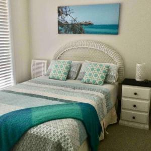 um quarto com uma cama com almofadas azuis e verdes em Cosy Cottage near the beach em Booker Bay