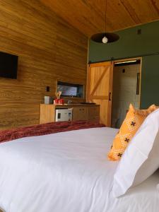 a bedroom with a white bed with wooden walls at Estalagem Santa Clara in Urubici