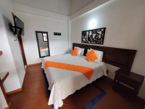 a bedroom with a bed with orange pillows on it at Hotel Cemandy by MA in Villa de Leyva