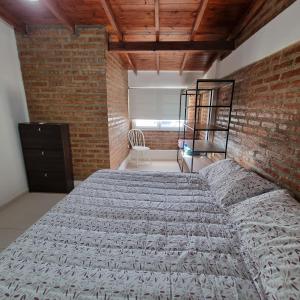 a bedroom with a bed and a brick wall at M&M Depto in Cipolletti