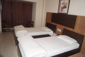 Habitación de hotel con 2 camas con sábanas blancas en CENTER POINT, en Rudrapur