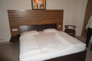 1 cama grande con almohadas blancas y cabecero de madera en CENTER POINT, en Rudrapur