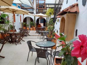 um pátio exterior com mesas, cadeiras e guarda-sóis em Hotel Cemandy by MA em Villa de Leyva