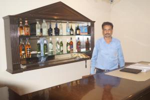 Ein Mann, der hinter einer Bar mit Alkoholflaschen steht. in der Unterkunft CENTER POINT in Rudrapur