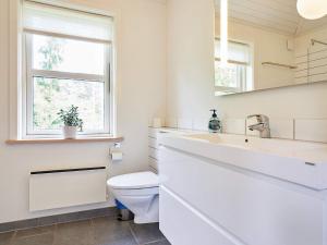 a white bathroom with a toilet and a sink at Holiday home Aakirkeby XXXV in Vester Sømarken