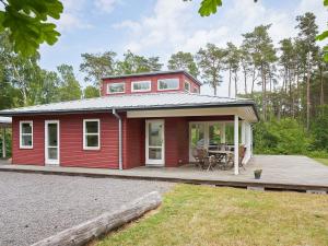 a red tiny house with a porch and a patio at 6 person holiday home in Aakirkeby-By Traum in Vester Sømarken