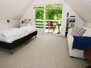 een slaapkamer met een bed en een bank op zolder bij Holiday home Hadsund CXXXIII in Hadsund