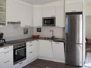 uma cozinha com armários brancos e um frigorífico de aço inoxidável em Holiday home SÄFFLE IV em Säffle